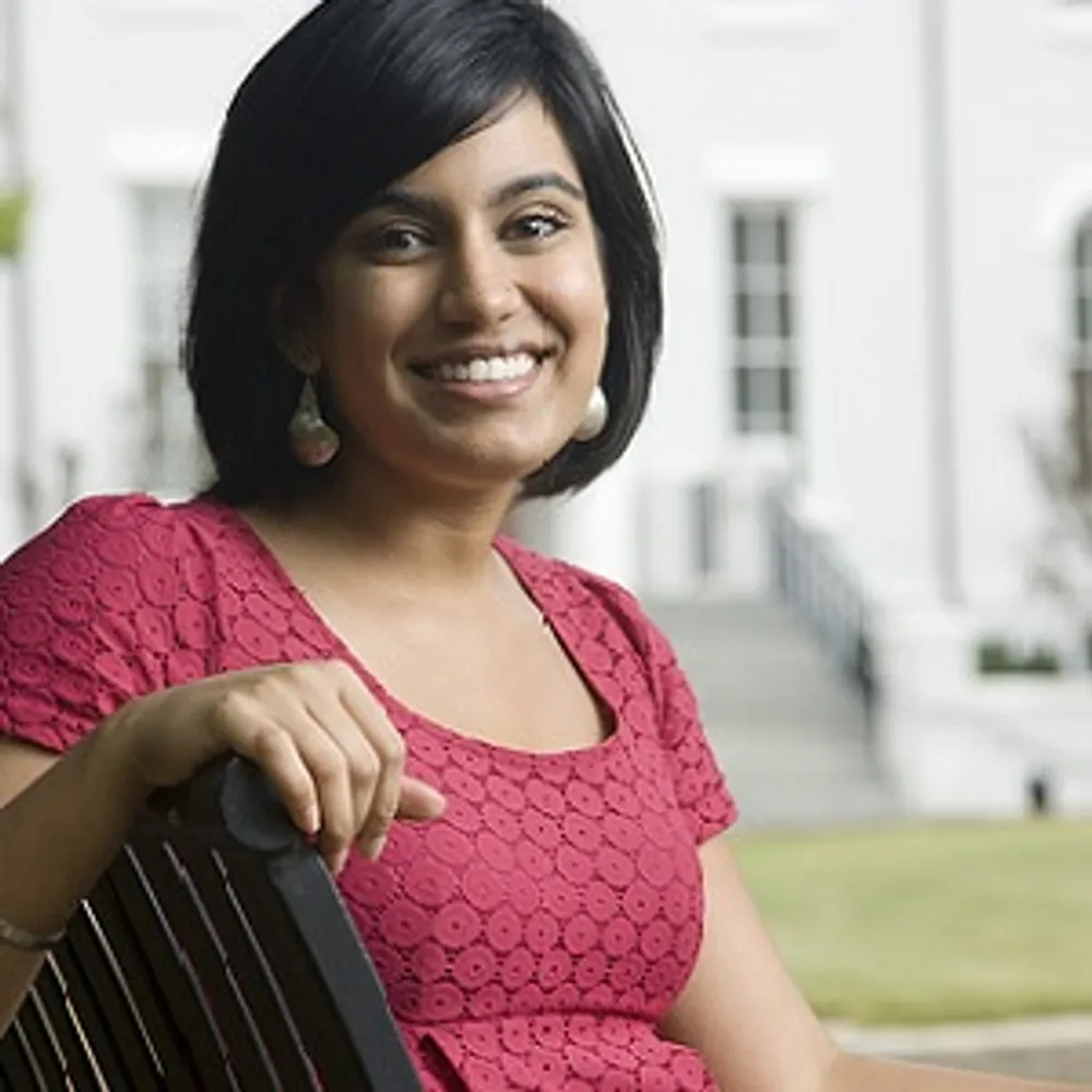 A student sitting in a chair looking at the camera smiling.