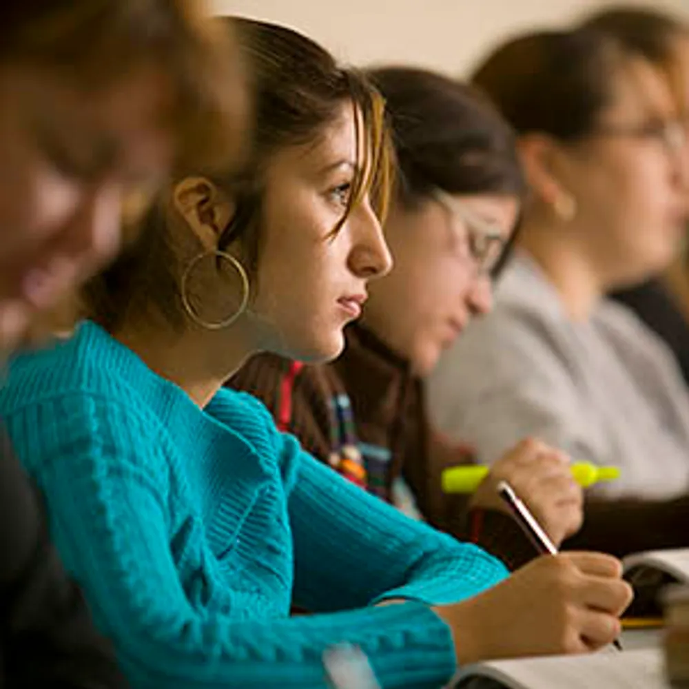 A site shot of two students in classroom listening to the teacher.
