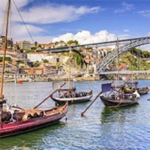 Boats pass beneath a bridge in Porto, Portugal.